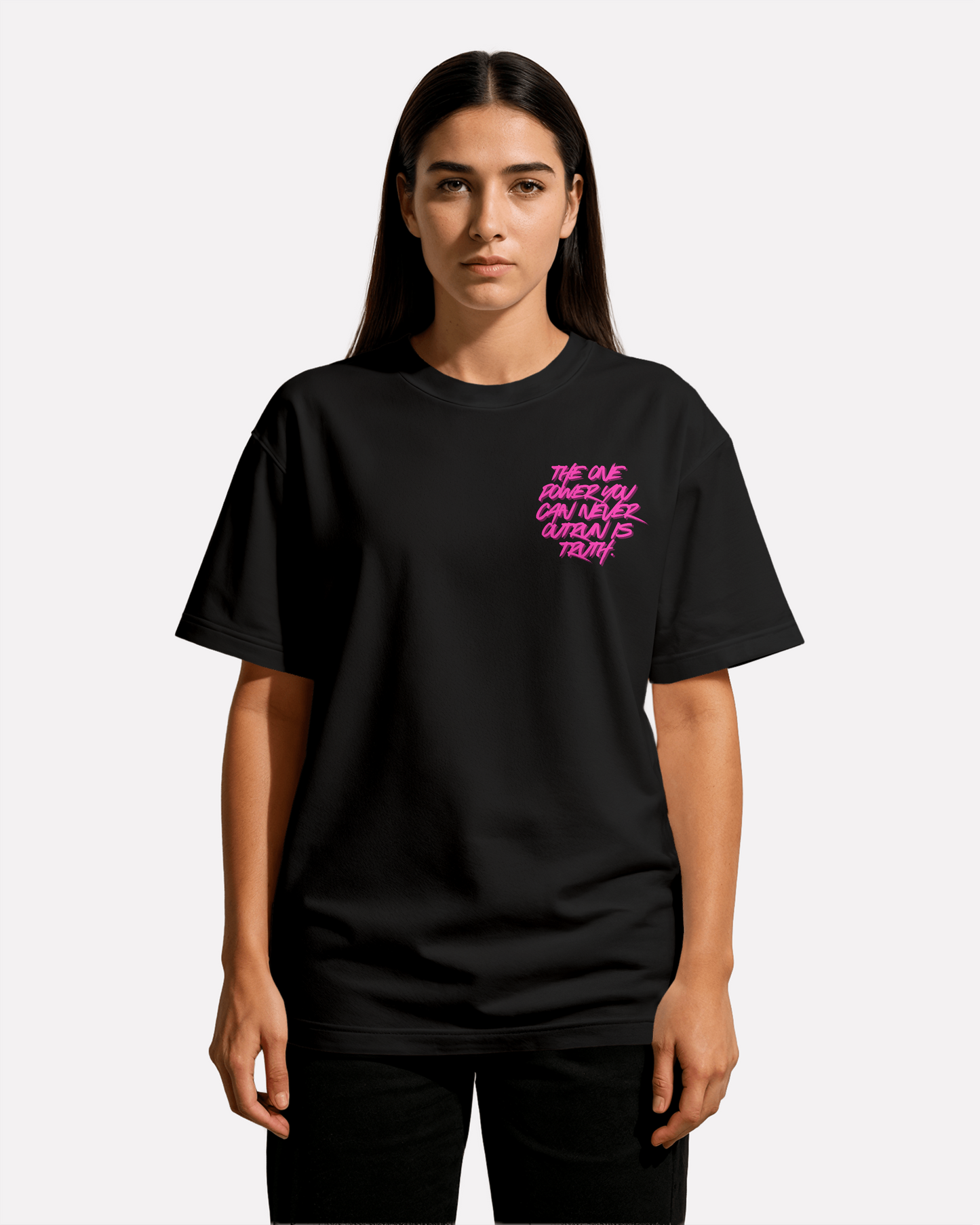 front view of model wearing black Third Journey oversized t-shirt featuring neon pink text reading “The one power you can never outrun is truth”