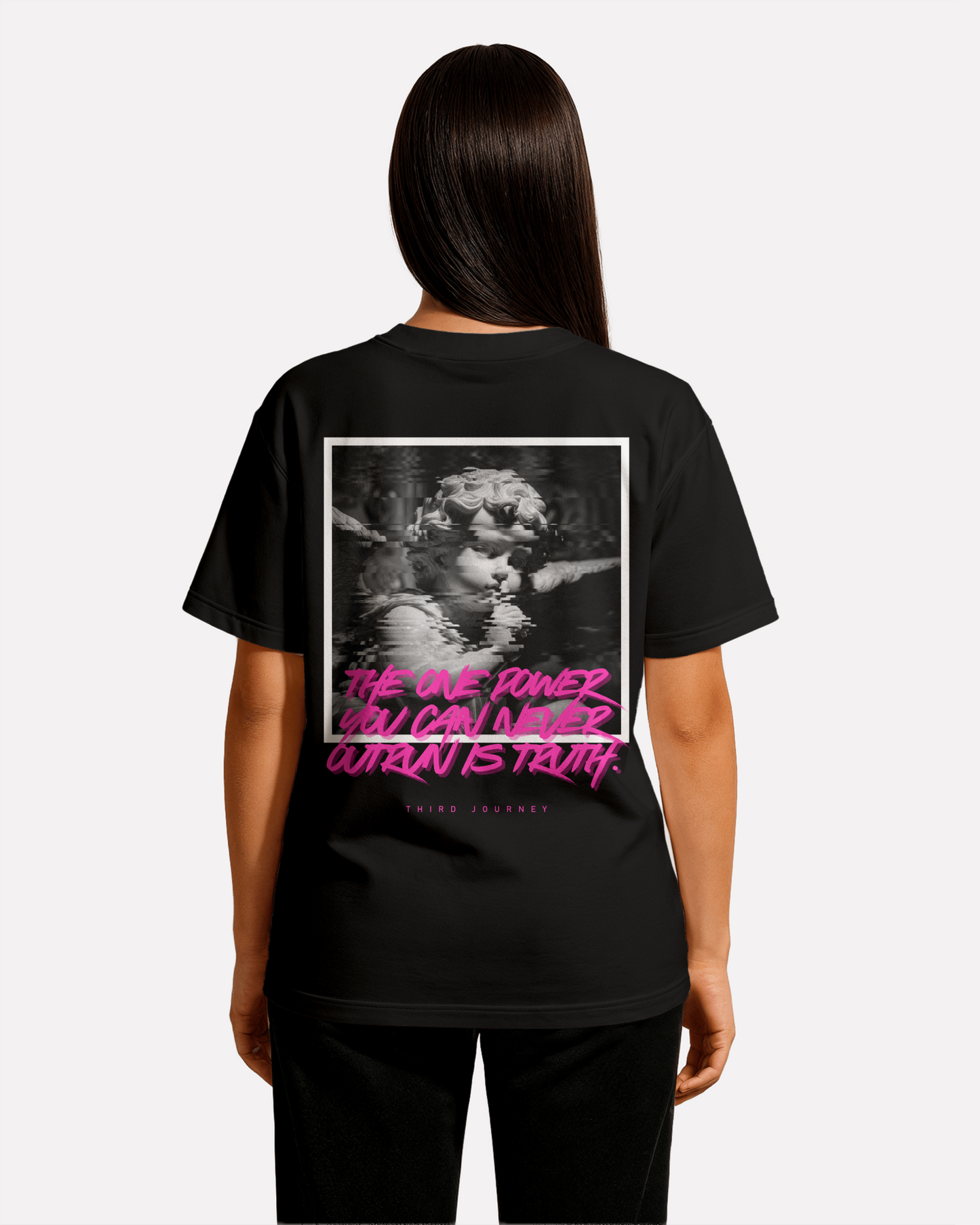 back view of model wearing black Third Journey oversized t-shirt featuring neon pink text reading “The one power you can never outrun is truth”